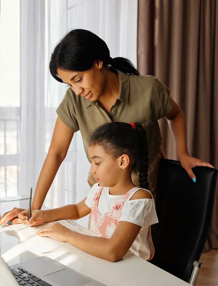 Photo of a mom overlooking her child's virtual reading lesson